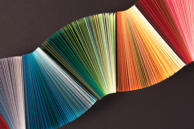 Striped Curled Colorful Paper Stacking and Waving on Dark Grey Background Overhead View, Close-up View.