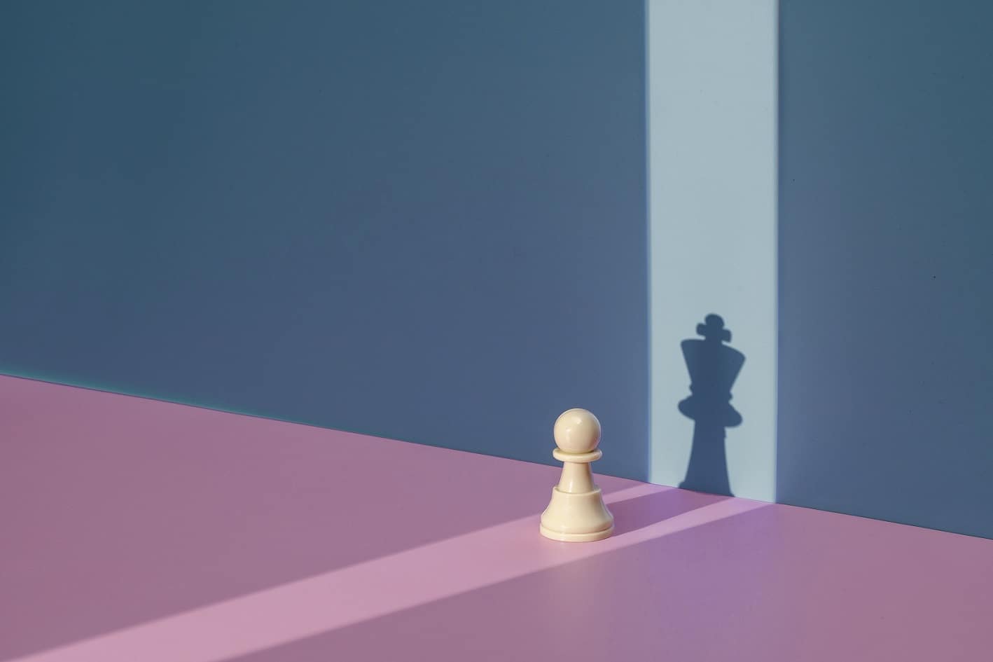 Bild eines Schachbauern, der im Schatten an der Wand der Schachkönig ist